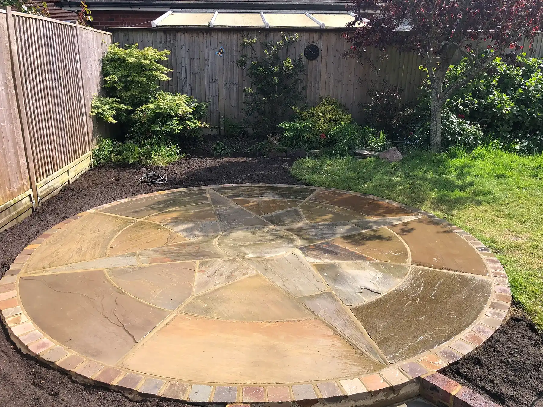 a circular stone patio in a back yard