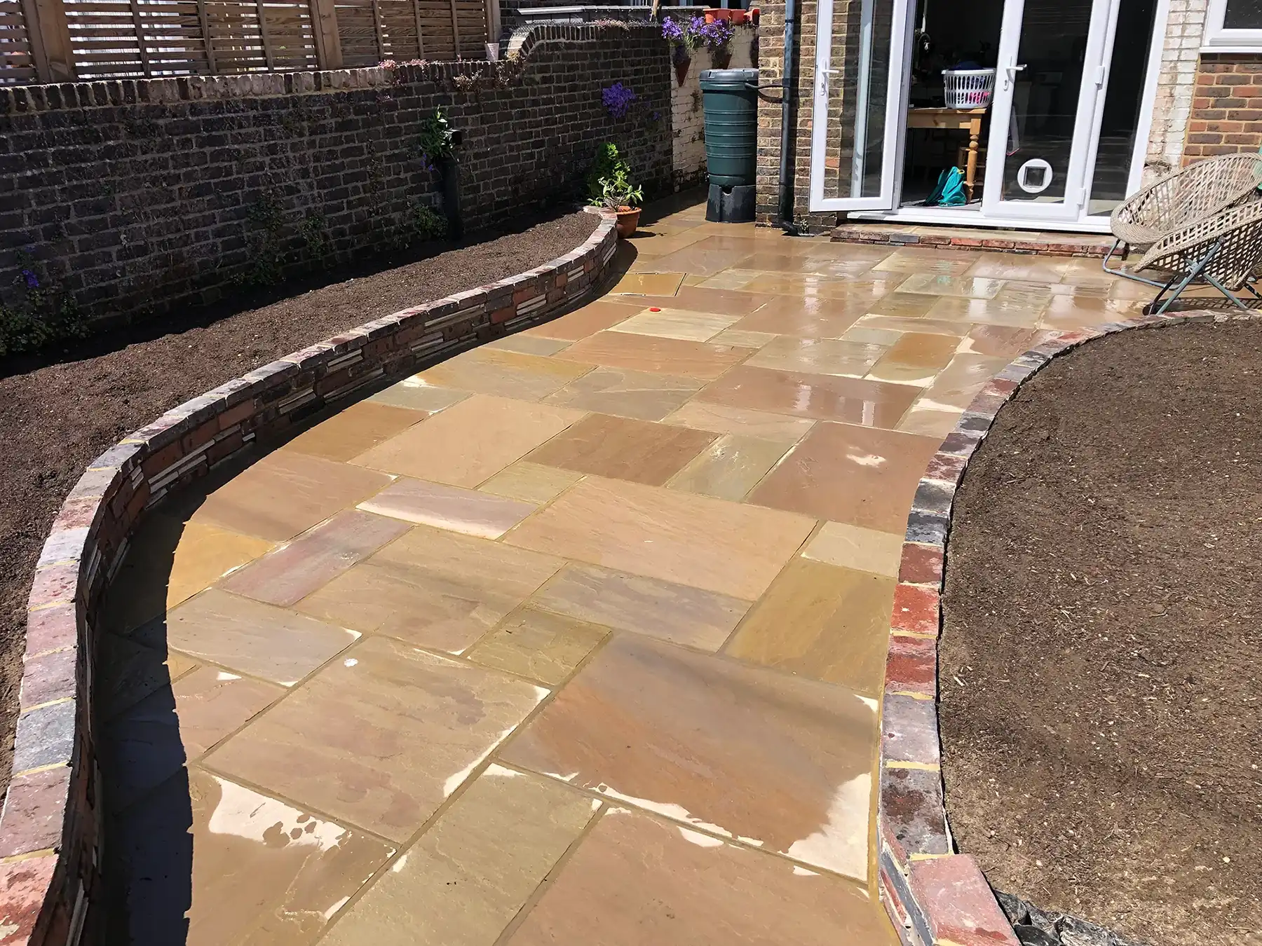 a patio with a brick wall and a stone walkway