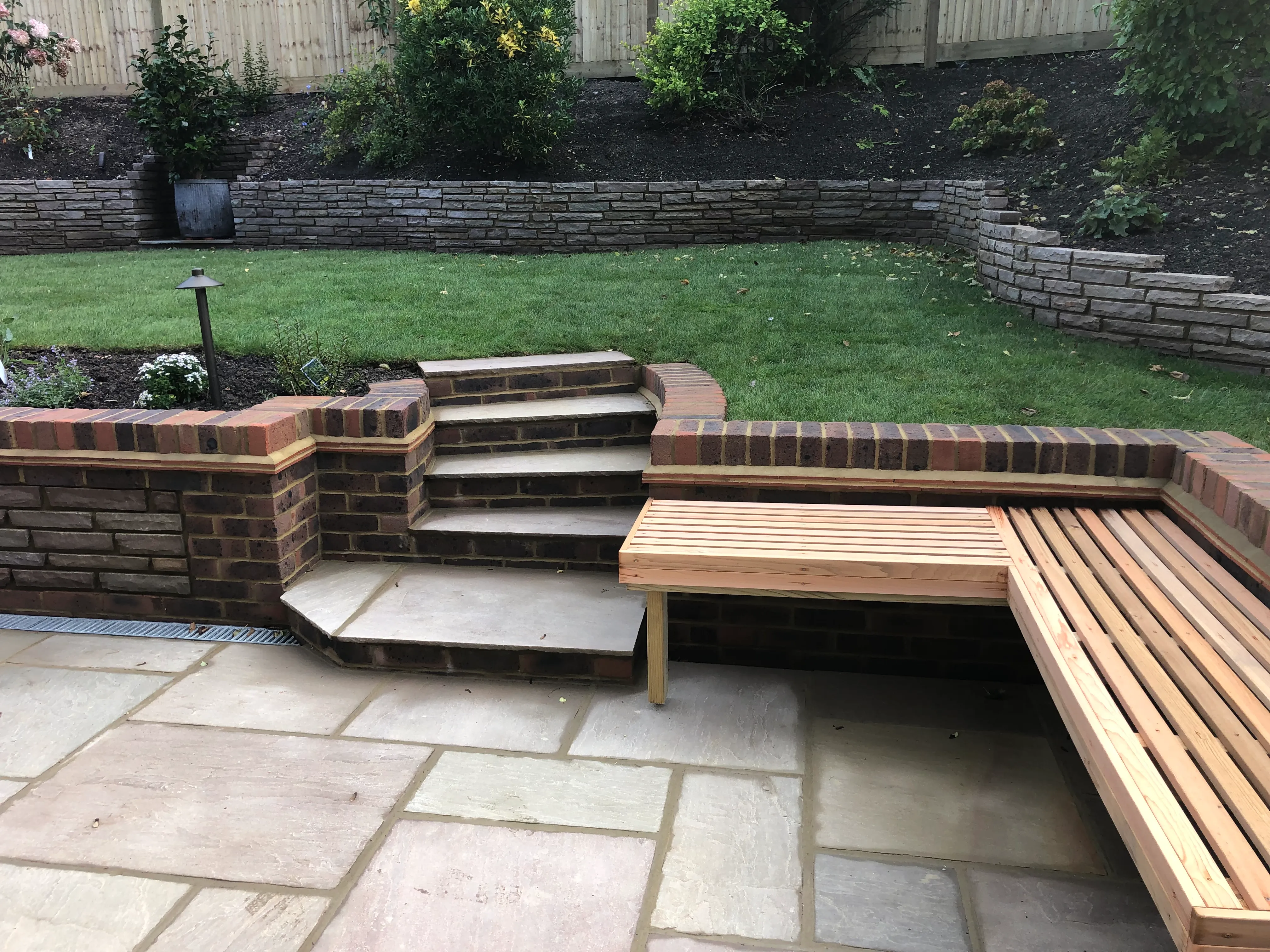 A wooden bench sitting next to a brick wall.